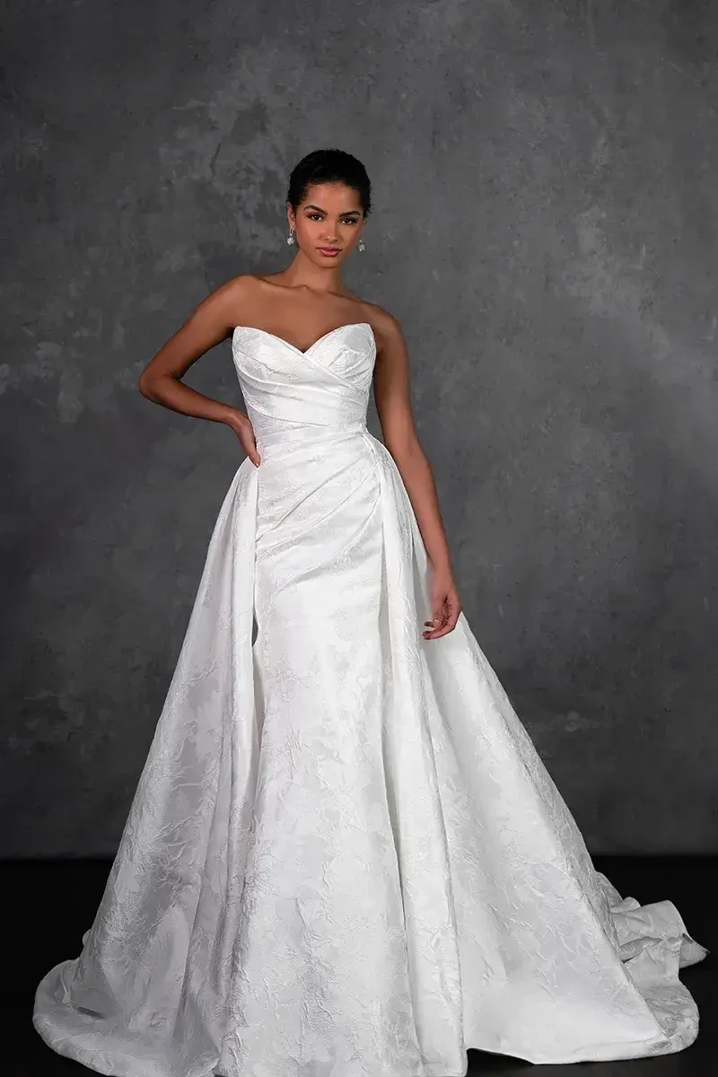 Model is wearing a satin fit-and-flare wedding dress with a sweetheart neckline and sleek, modern silhouette.