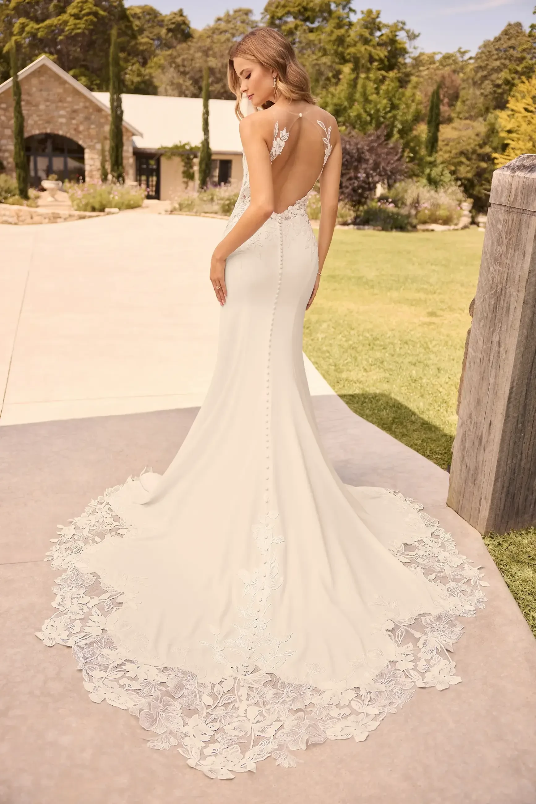 Model is wearing a dress with a high illusion lace neckline, sequined lace bodice, fit-and-flare crepe skirt, and a low illusion keyhole back.